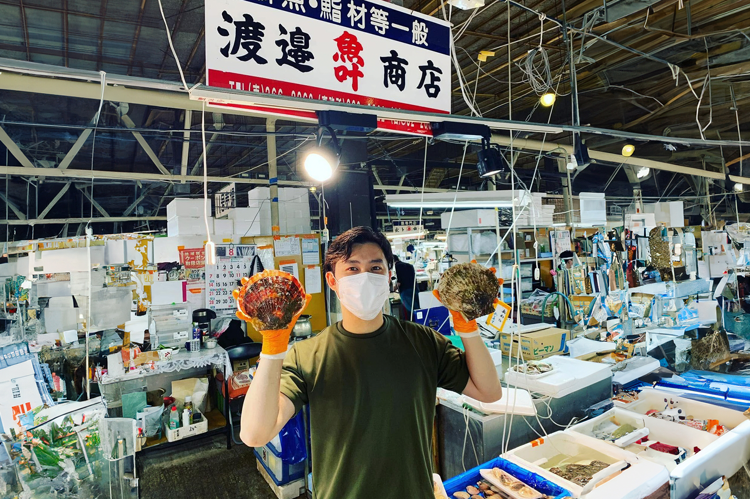塩釜の市場で貝を手に持つ渡邉商店の方